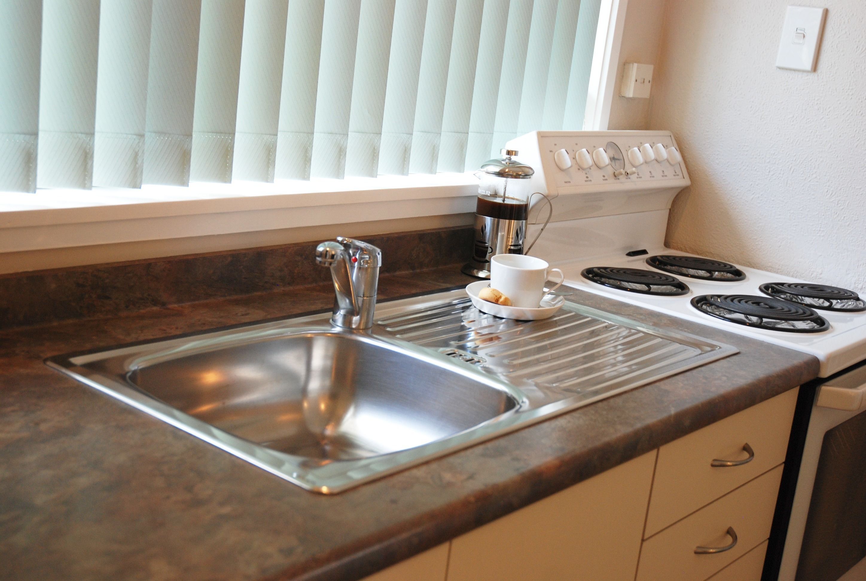 A kitchen with a stainless steel sink, a coffee maker, and a stove.