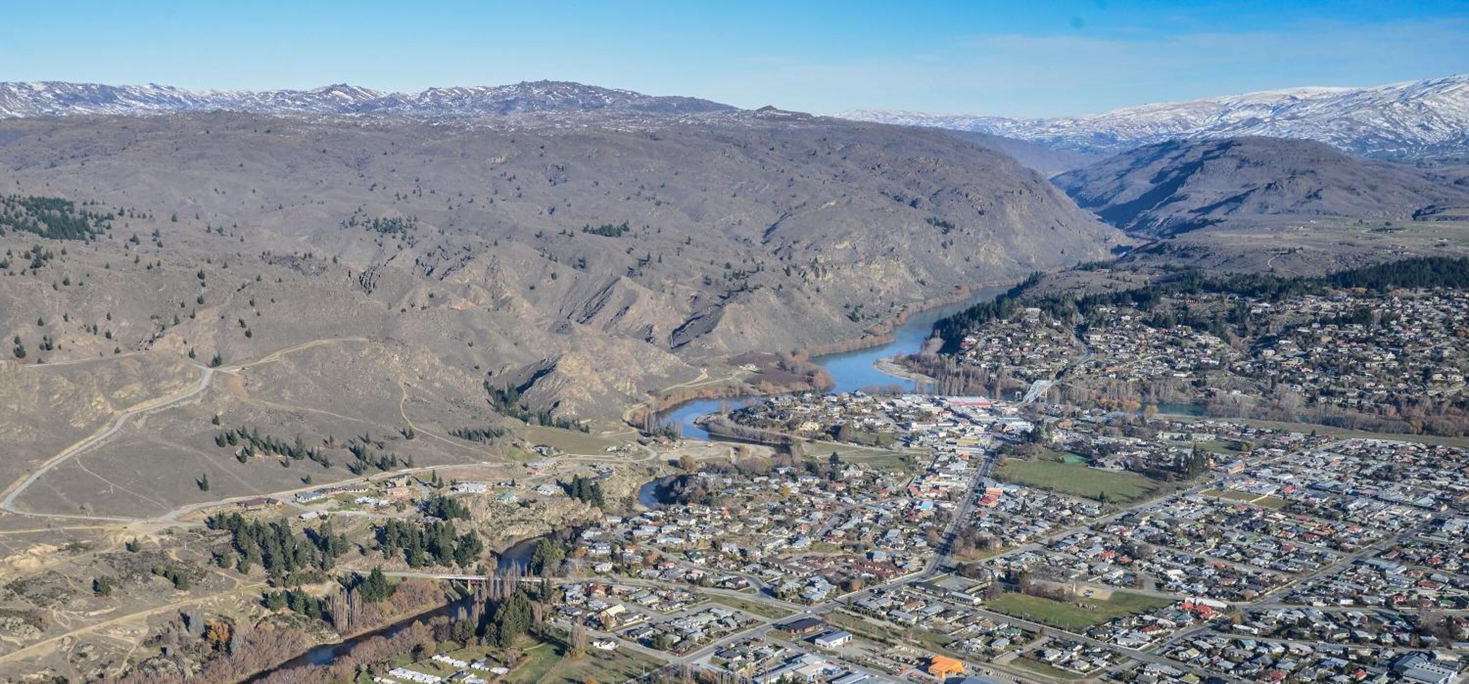 Luftaufnahme einer Stadt mit Fluss, Bergen und einer Mischung aus Wohn- und Geschäftshäusern.