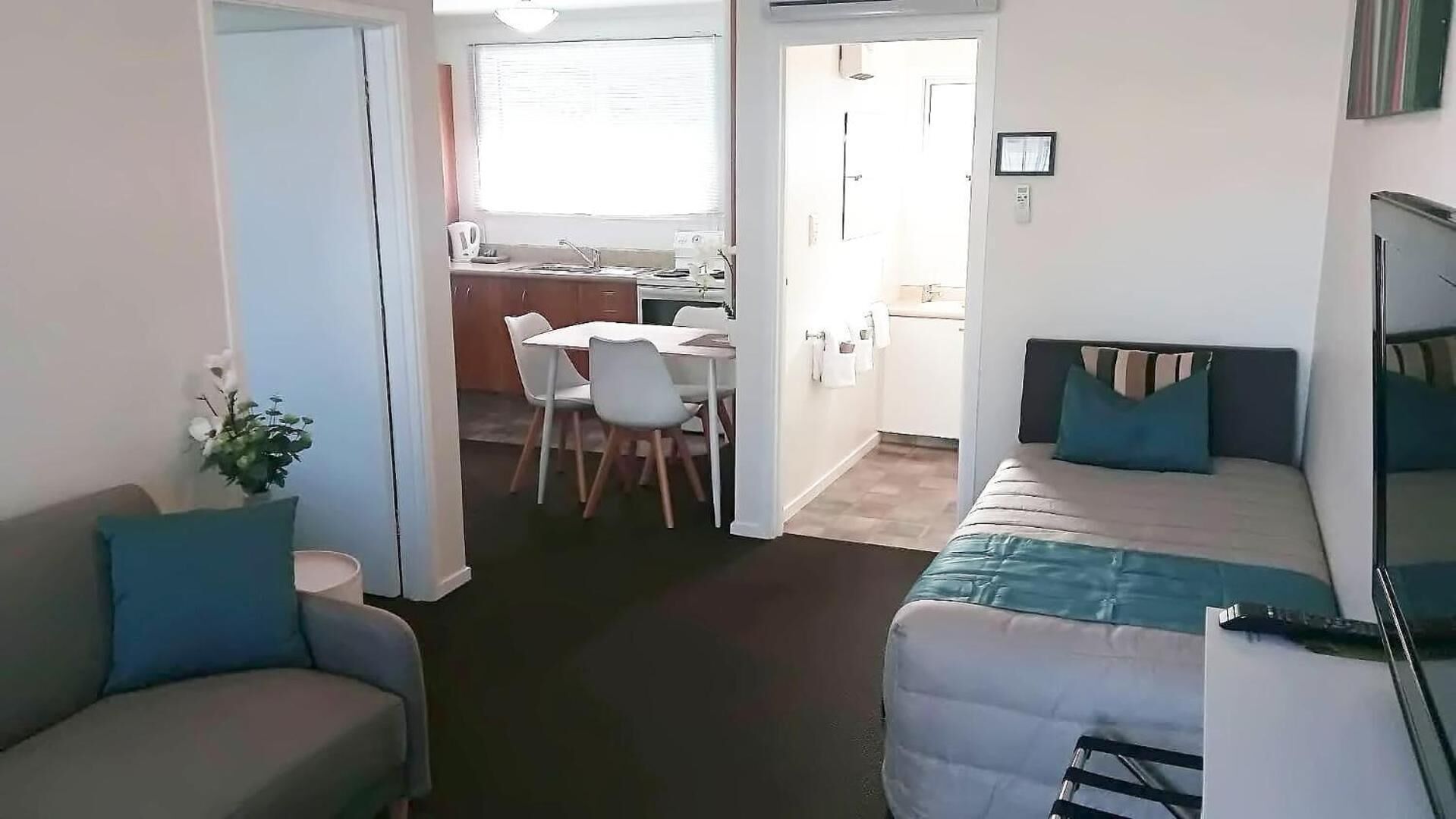 A compact living space with a kitchenette, a dining area, and a bed.