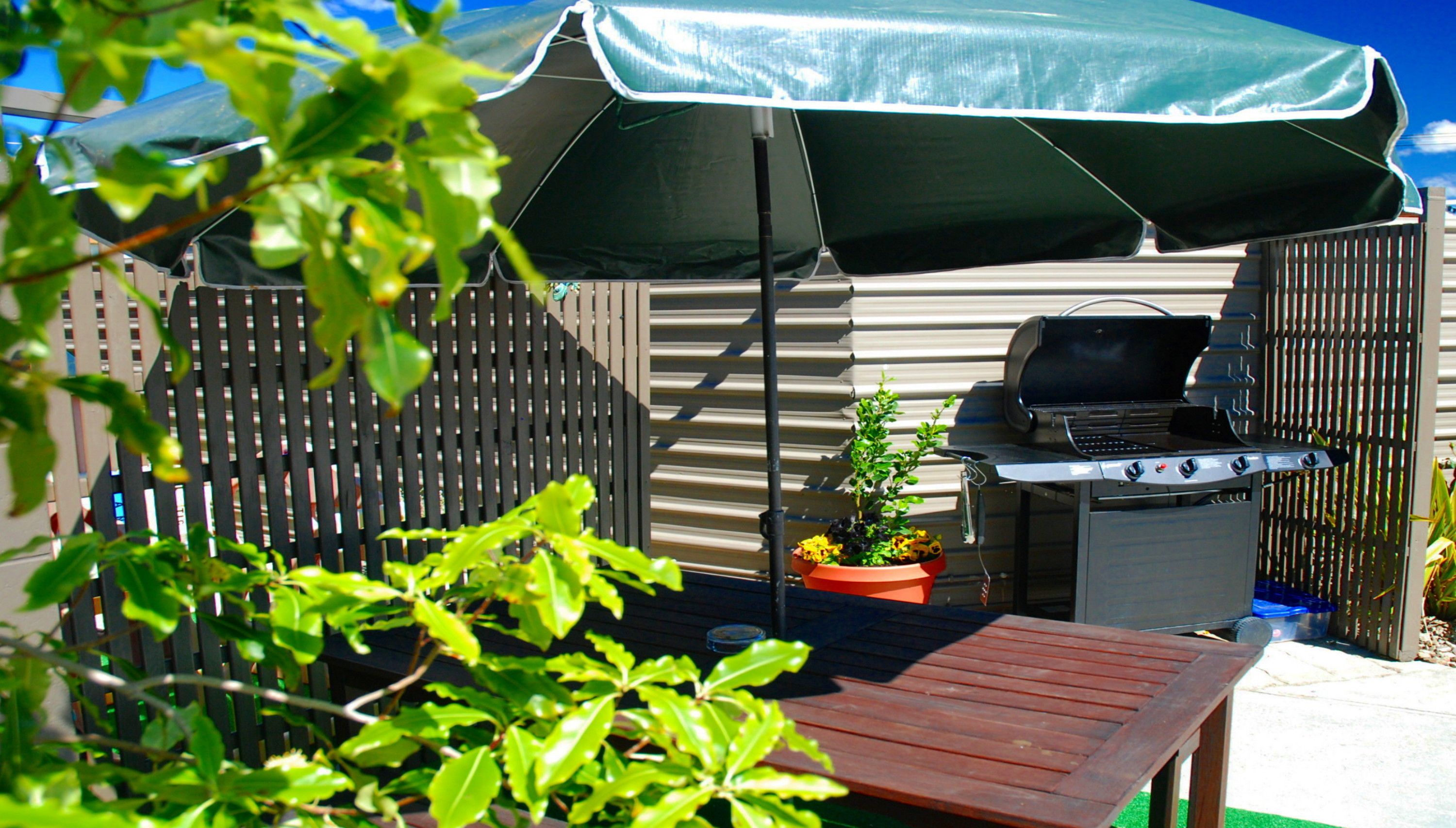 A backyard with a barbecue grill, a wooden table, and a potted plant.