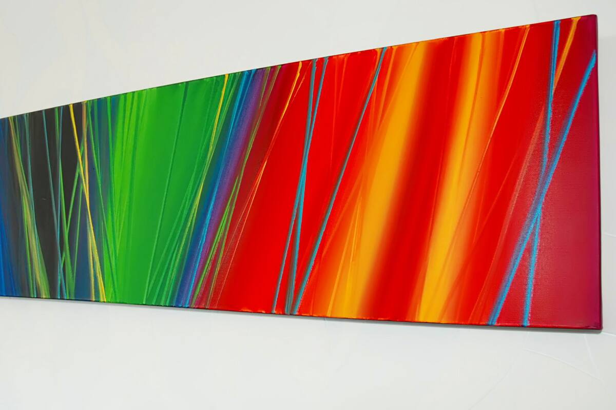 Un cuadro abstracto largo y estrecho, con colores vivos, sobre una pared blanca.