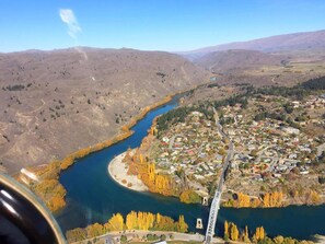 A river winding through a town with a bridge, surrounded by hills.
