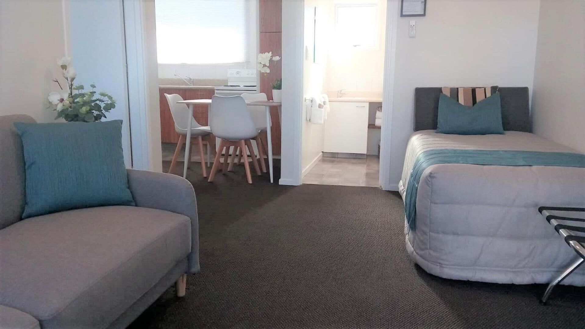 Et hotelværelse med en sofa, seng, skrivebord og stol.