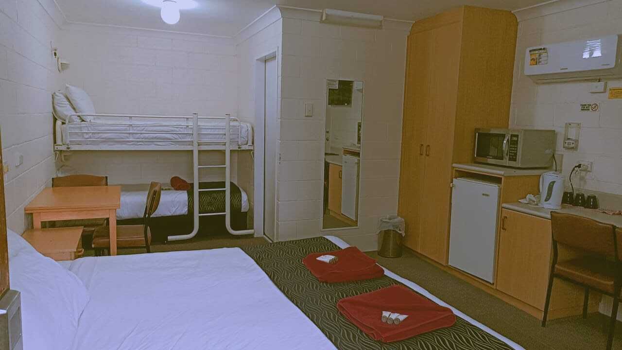 Ein Hotelzimmer mit Etagenbett, Schreibtisch, Mikrowelle und einer kleinen Küchenzeile.