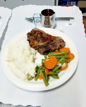 Ein Teller mit Kartoffelpüree, grünen Bohnen, Karotten und einem Steak.