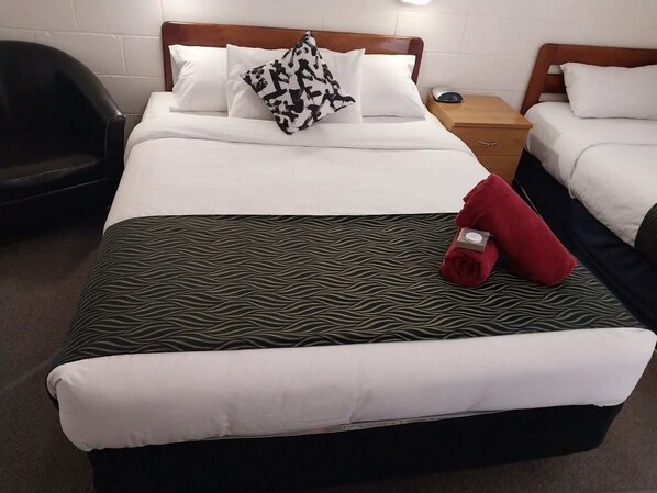Ein Hotelzimmer mit einem großen Bett, zwei Nachttischen, einem Sessel und einem Beistelltischchen mit Lampe.