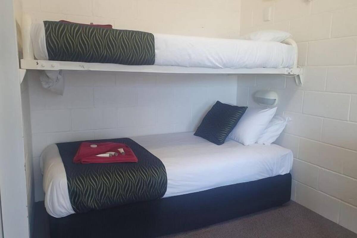 A bunk bed room with white walls, a white ceiling, and a small window.