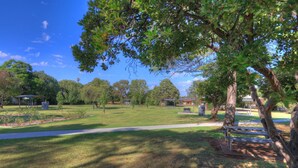 Un parque con un sendero pavimentado, mesas de picnic y un pabellón.