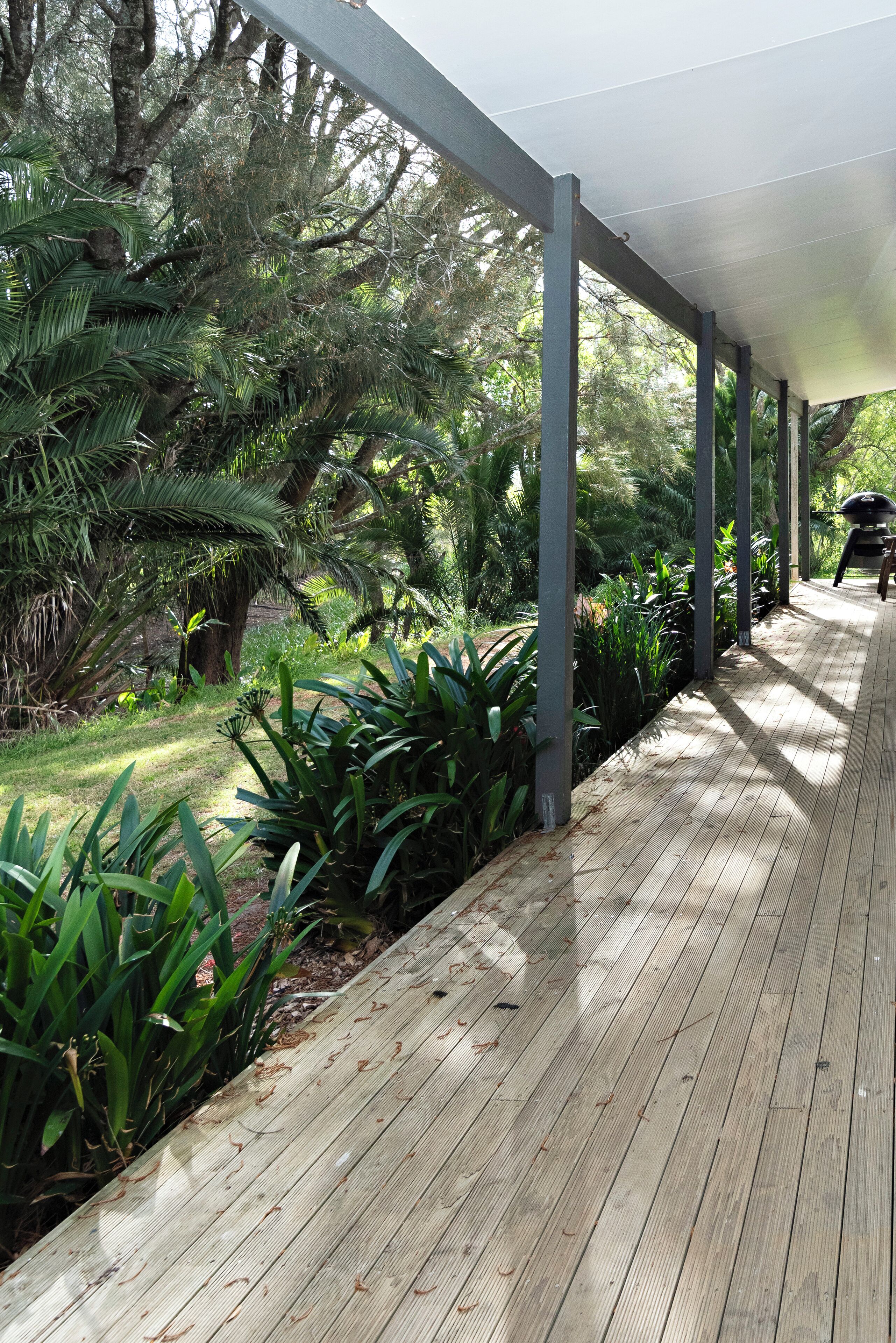 Una terraza cubierta de madera con vistas a la vegetación tropical y una silla.