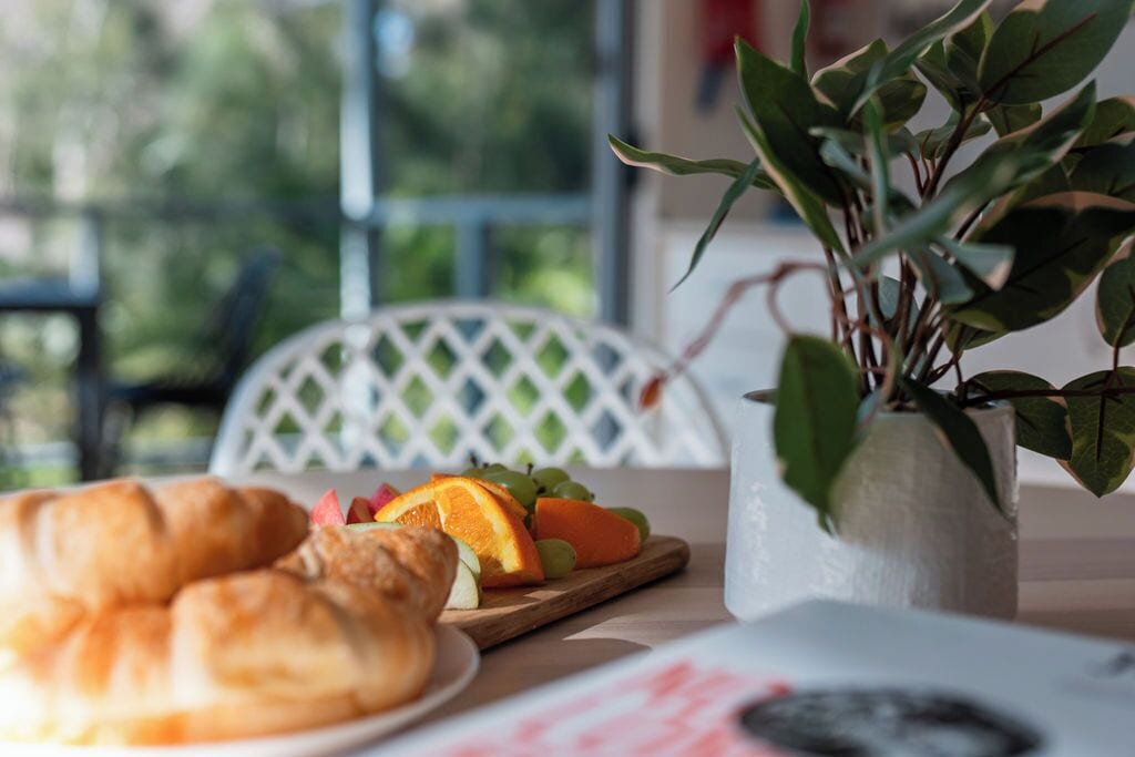 A table with croissants, a fruit platter, and a potted plant.