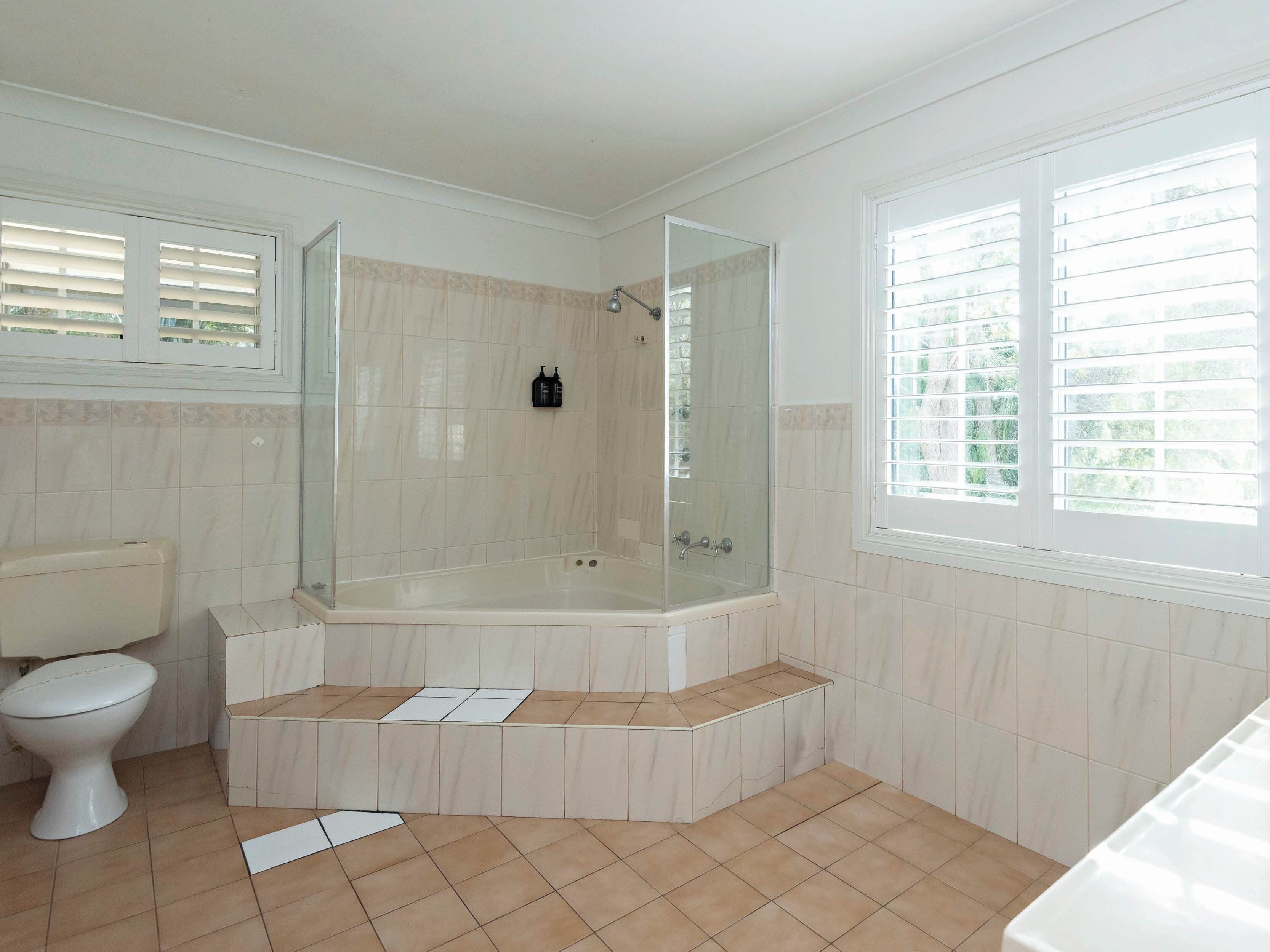 Un baño con ducha envuelta en vidrio, inodoro y bañera.