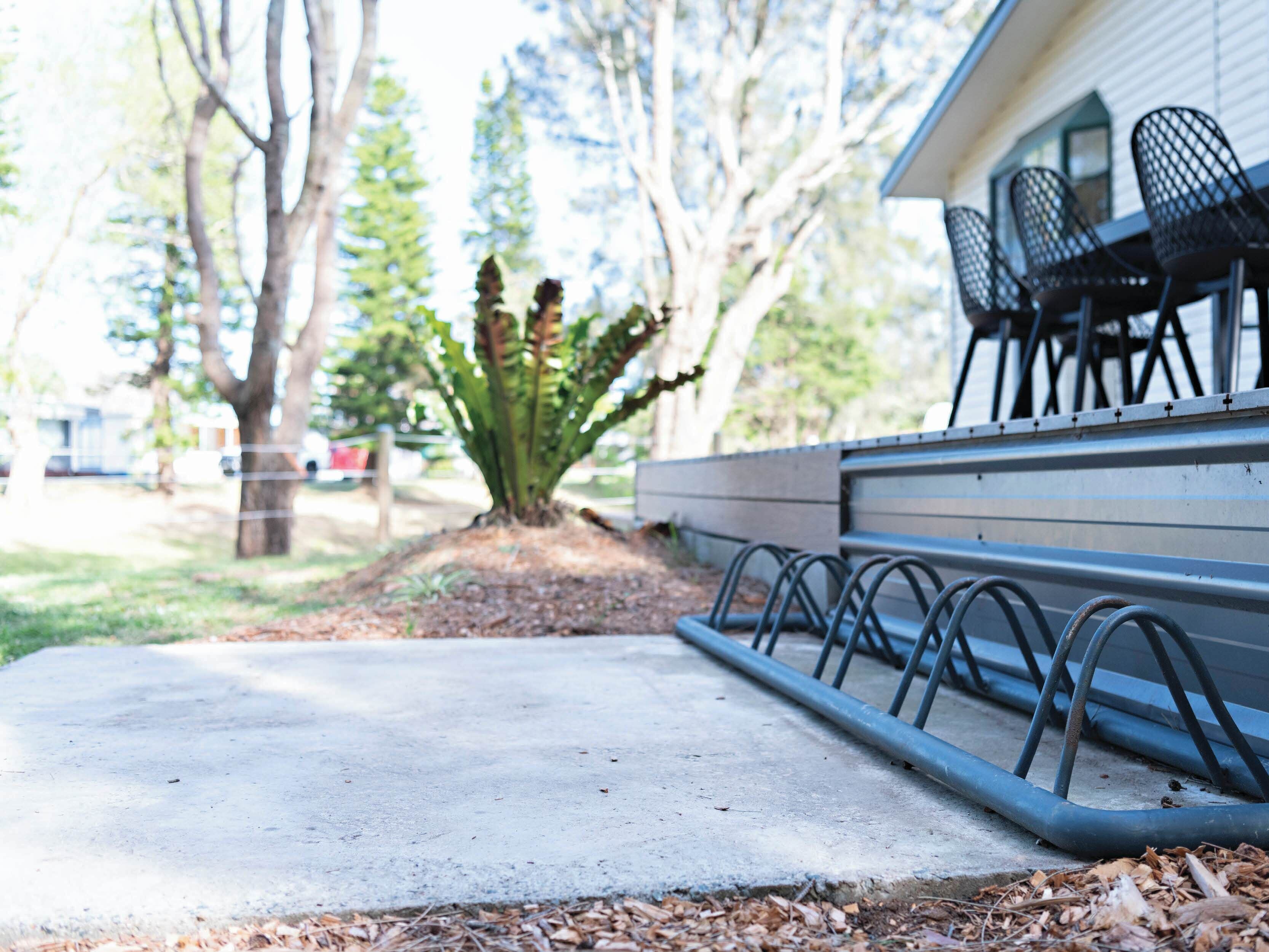 A concrete pathway leading to a building with a row of black metal chairs on the right.