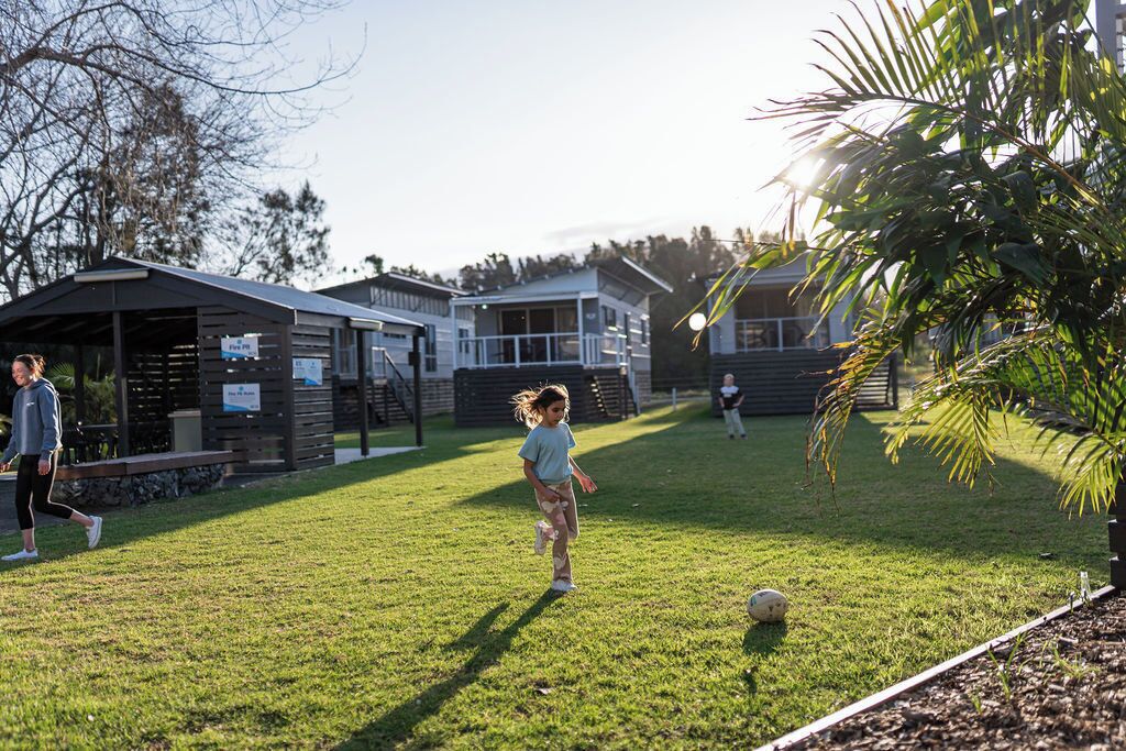 A grassy area with a playground and a building with a covered seating area.
