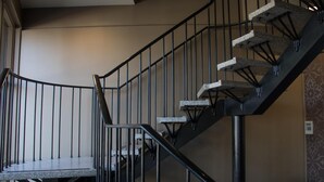 Eine Treppe mit Metallgeländer und Steinstufen, die zu einer oberen Etage führt.