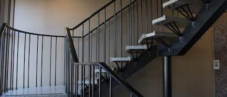 A staircase with a metal railing and stone steps, leading to an upper floor.