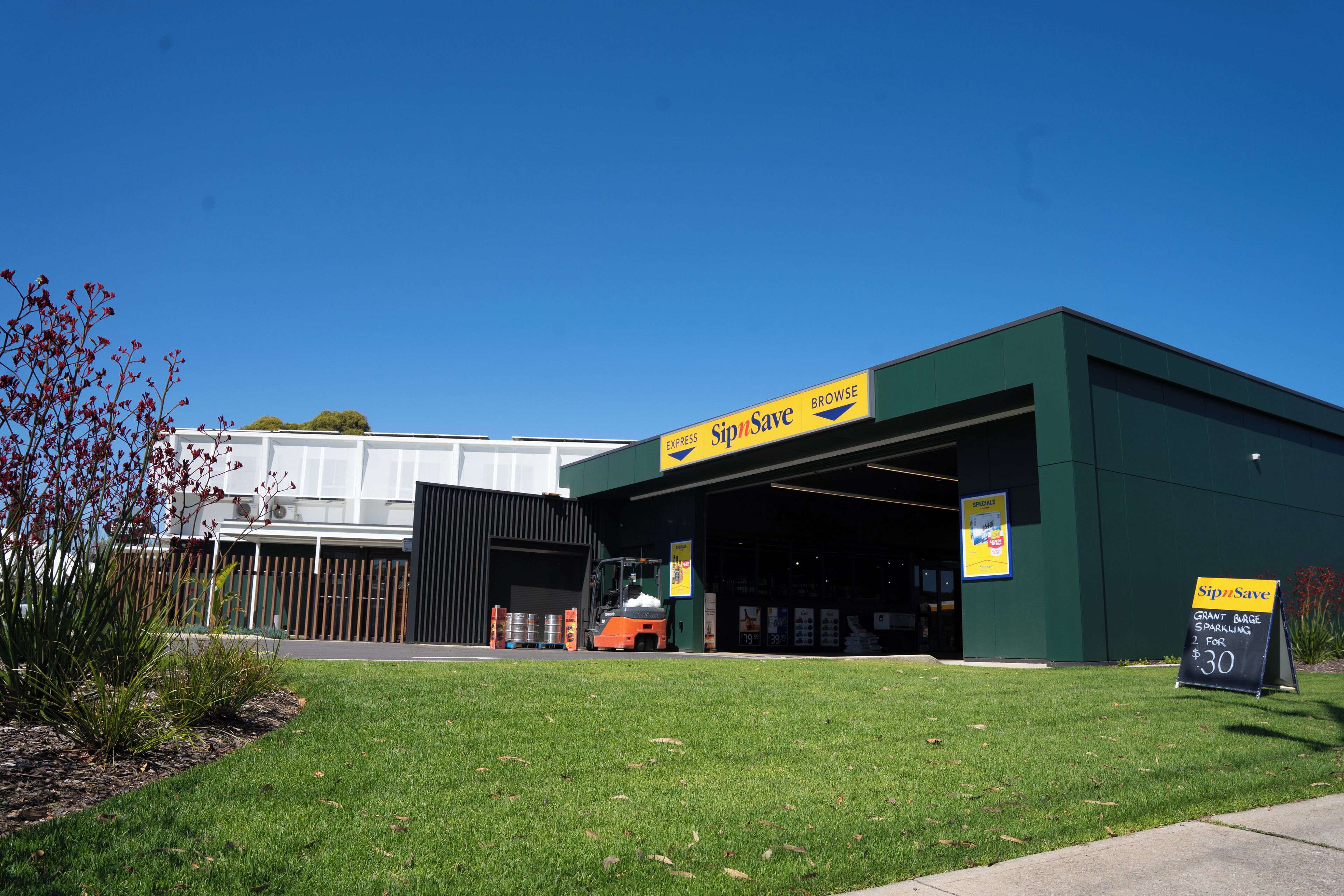 A commercial building with a green facade and a yellow sign reading "SipSave".