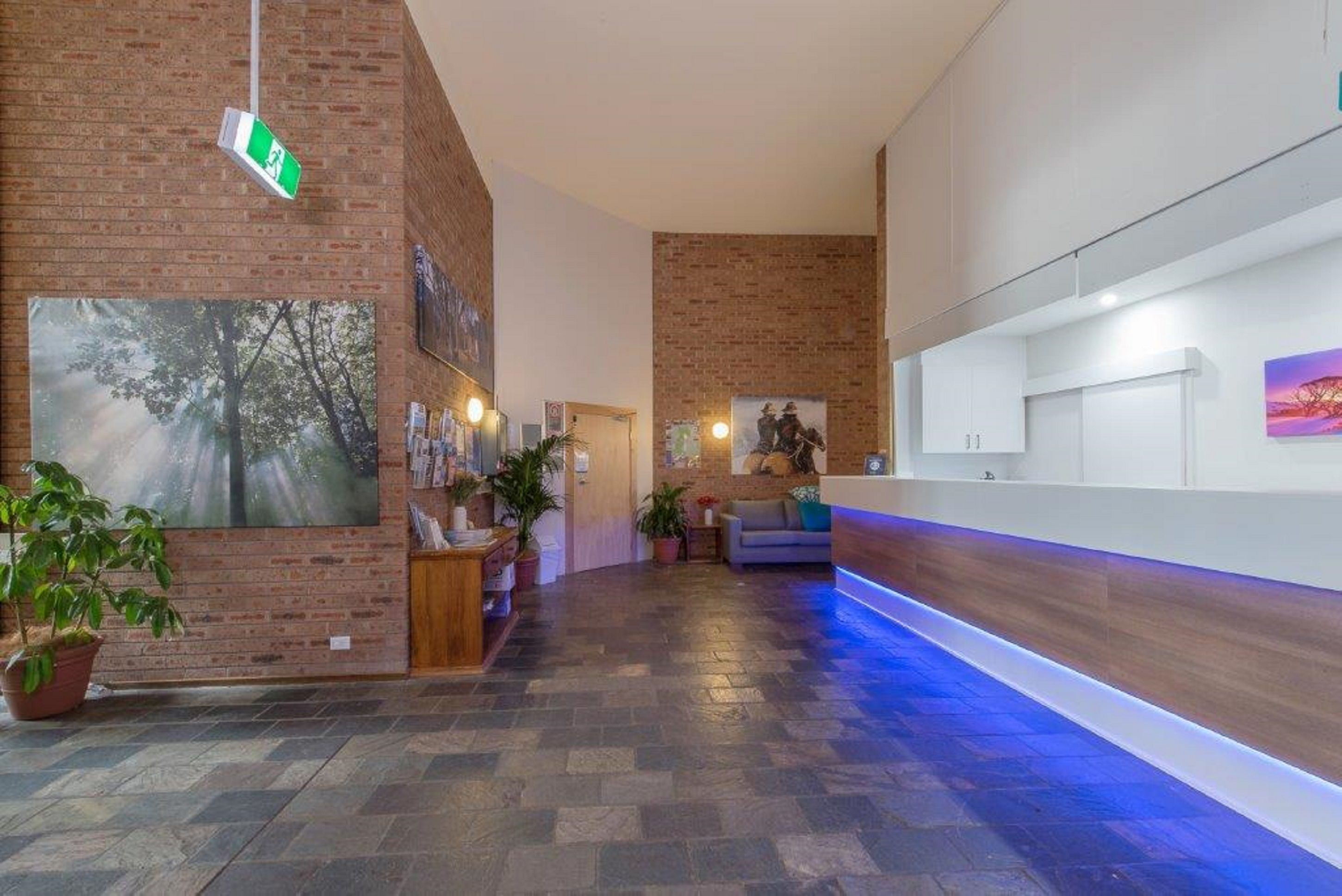 A hotel lobby with a brick wall, a reception desk, and a blue-lit reception area.