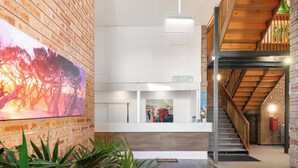 A reception area with a brick wall, a large painting, a reception desk, and a staircase.