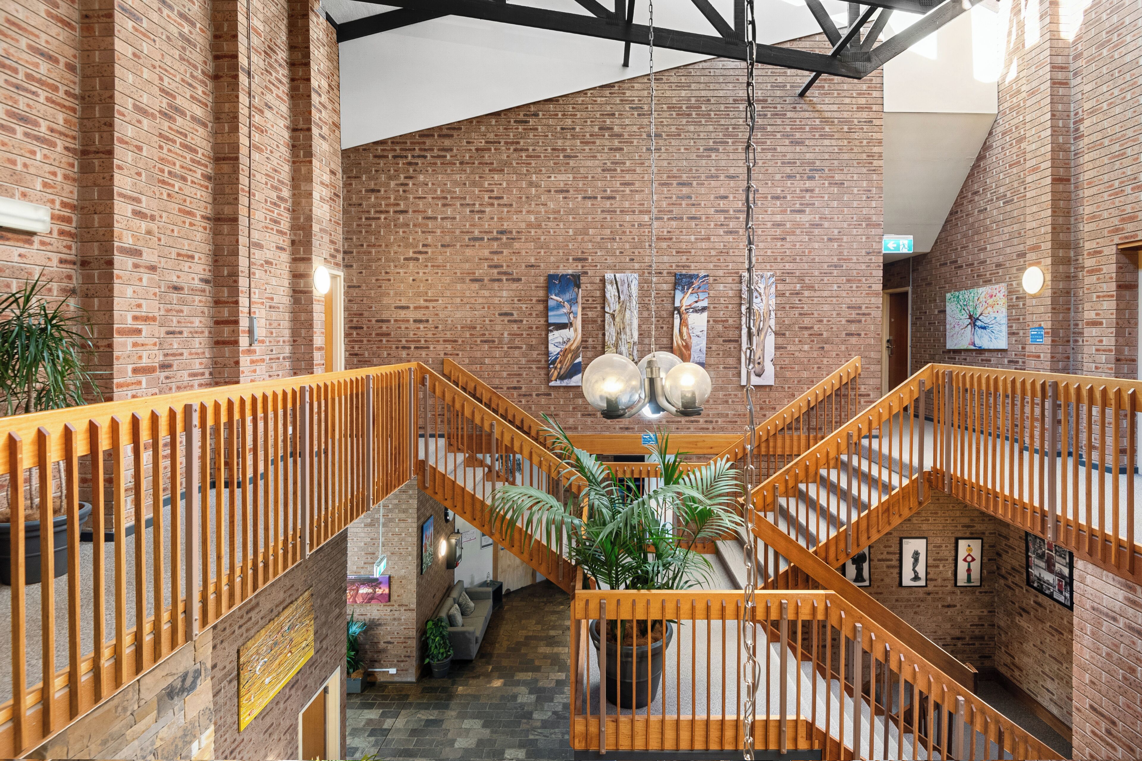 A multi-level interior with exposed brick walls, wooden railings, and a central staircase.