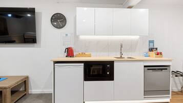 Una cocina compacta con armarios blancos, horno integrado y lavavajillas.
