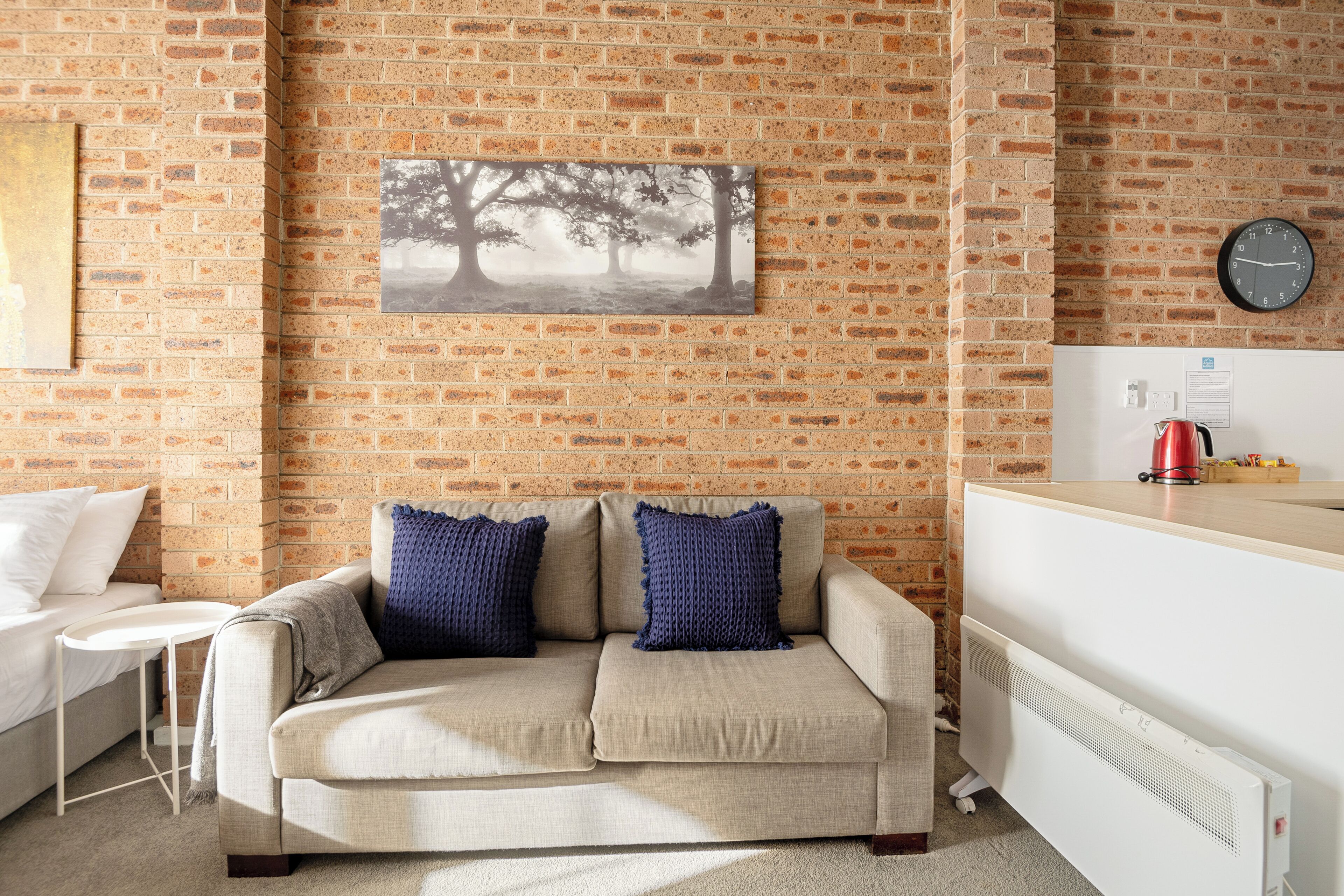 A living room with a brick wall, a sofa, a small table, and a radiator.