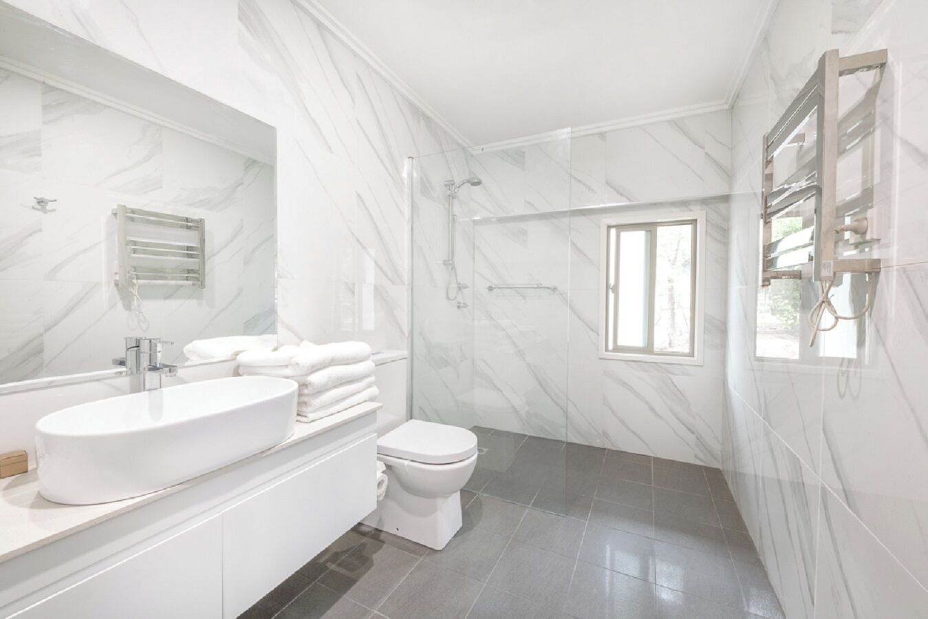 Un baño moderno con un lavamanos blanco grande, un inodoro y una ducha.