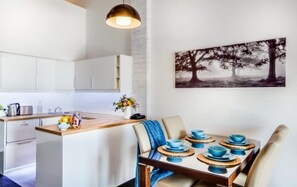 Een moderne keuken met witte kasten, een houten eiland en een eethoek met een tafel gedekt voor vier personen.