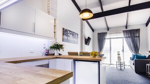 A modern kitchen with a wooden countertop, a built-in dishwasher, and a pendant light.