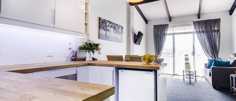 A modern kitchen with a wooden countertop, a built-in dishwasher, and a pendant light.