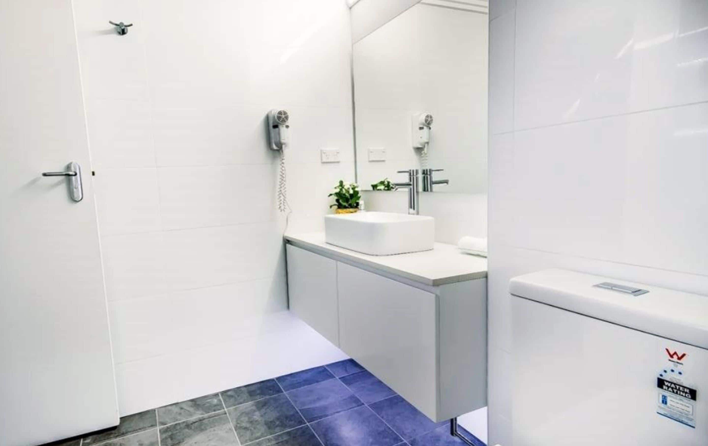 Une salle de bain moderne avec un lavabo blanc, un miroir et des toilettes.