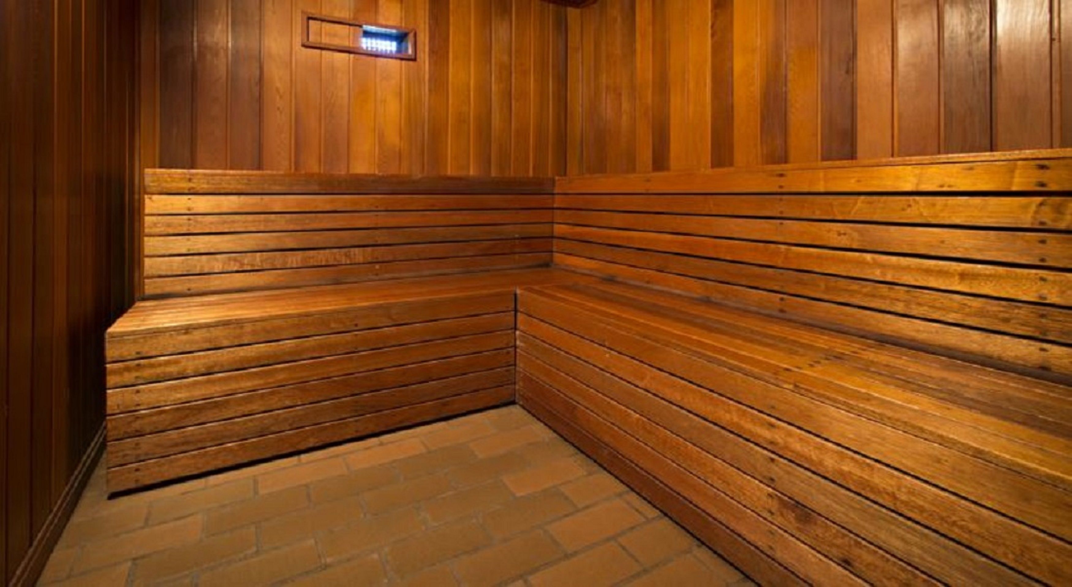 Een sauna met houten banken en een vloer van baksteen.