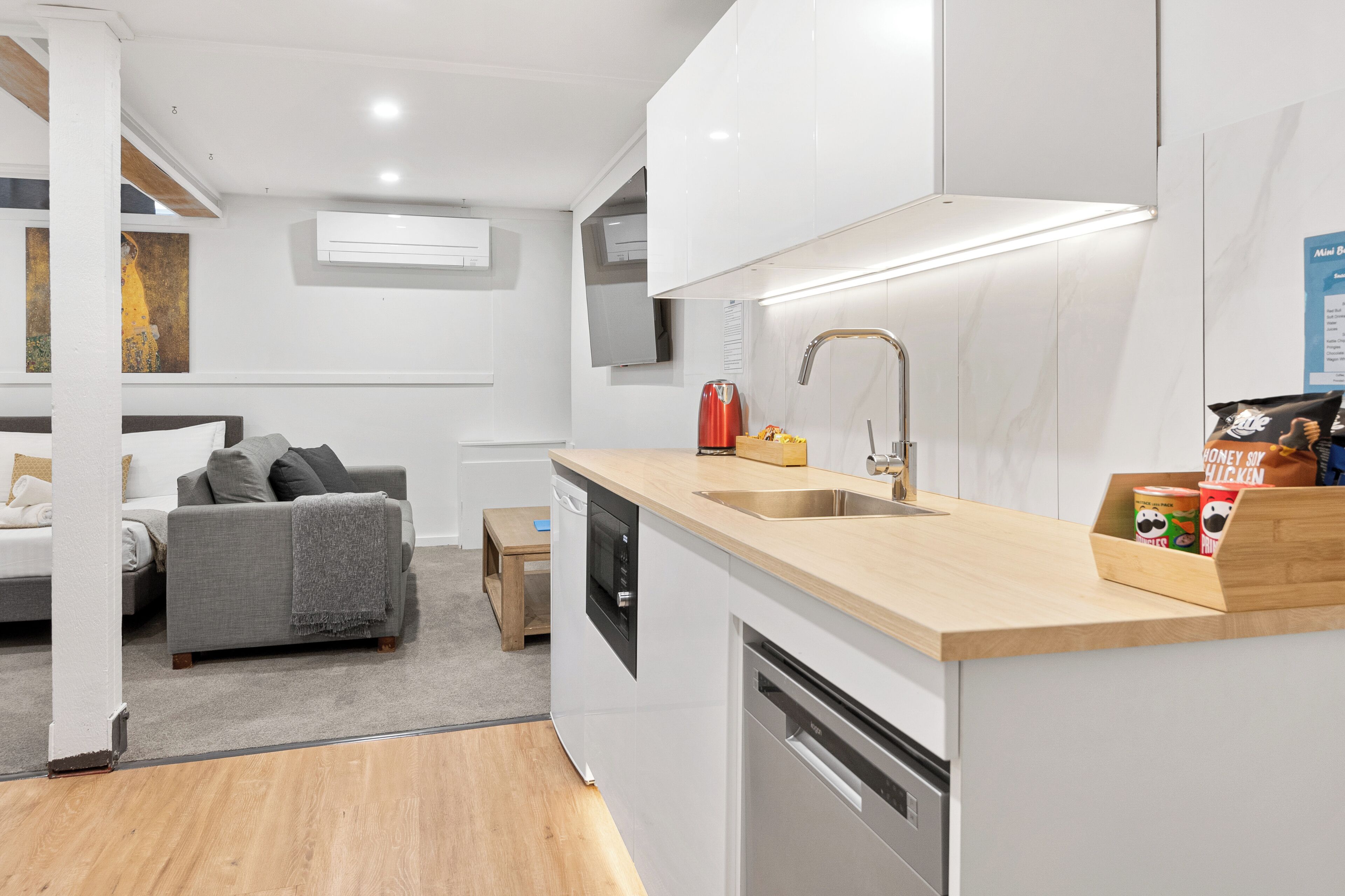A compact kitchen with a dishwasher, sink, and wooden countertop.