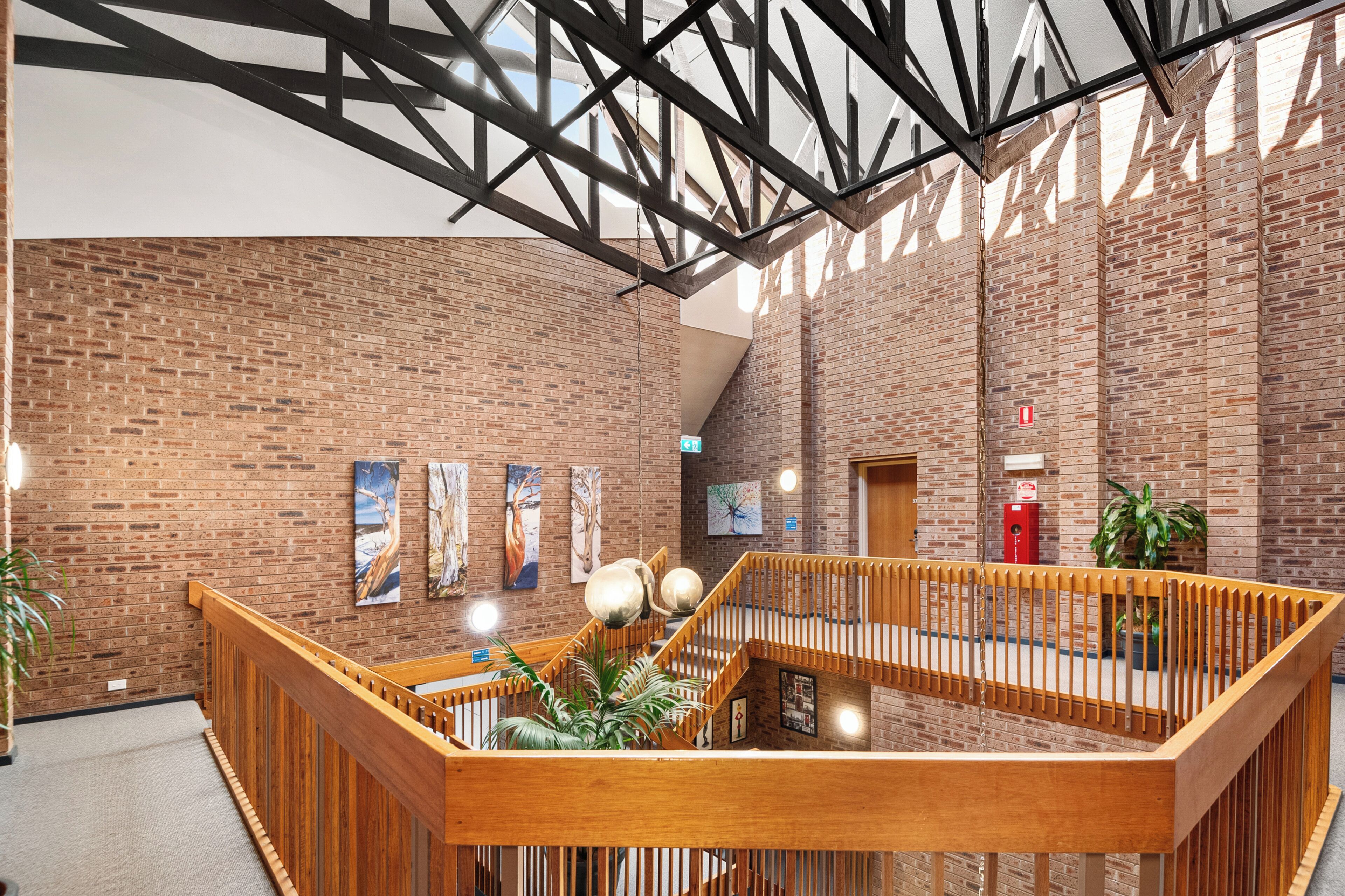 Een ruime lobby met zichtbare bakstenen muren, houten balustrades en kunstwerken aan de wanden.
