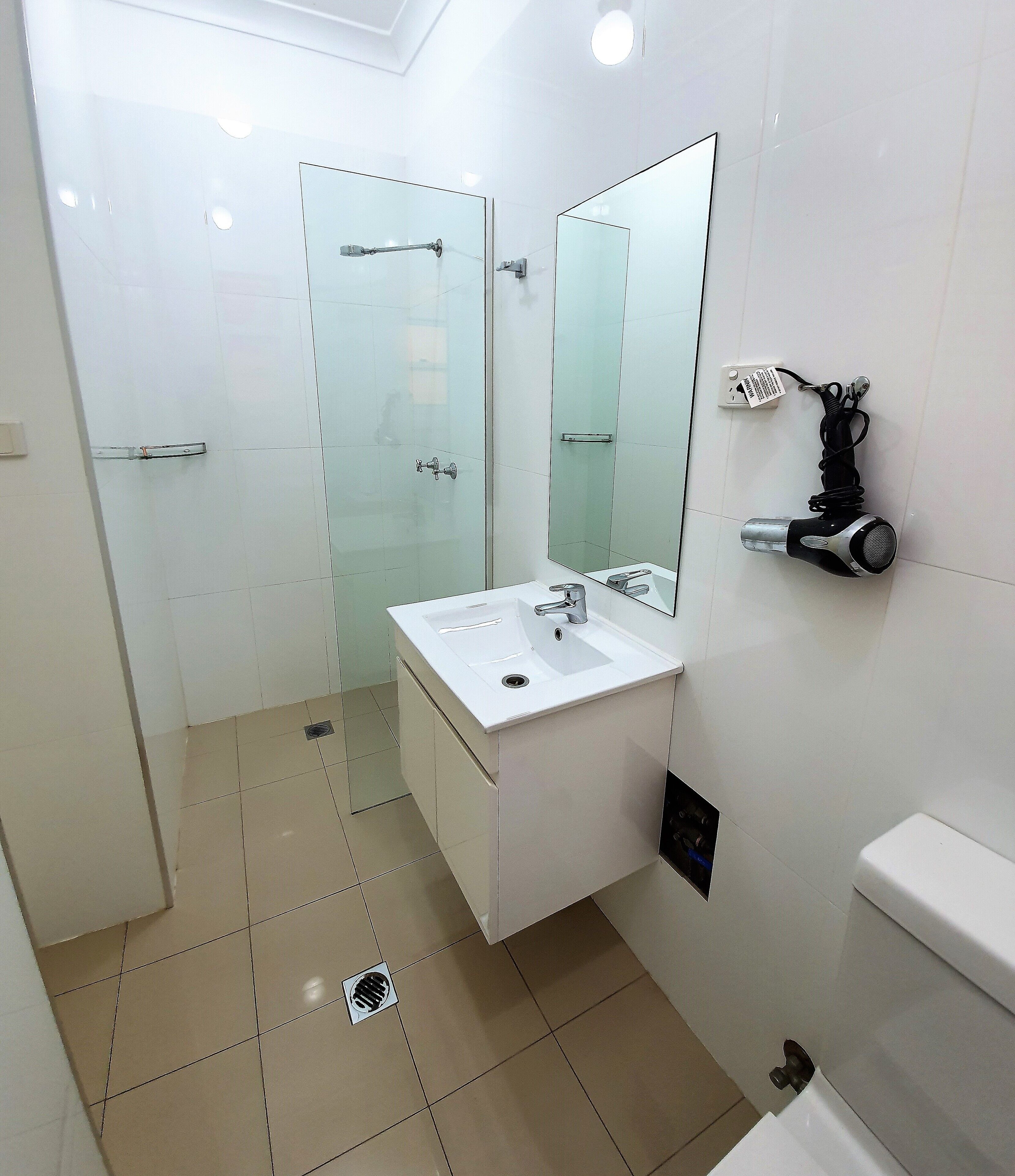 A modern bathroom with a white sink, mirror, and toilet.