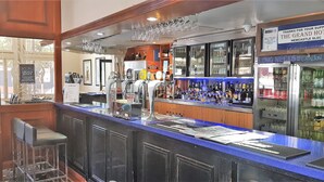 A bar area with a counter, stools, and a refrigerator stocked with bottles. - The Grand Hotel Newcastle (Newcastle)