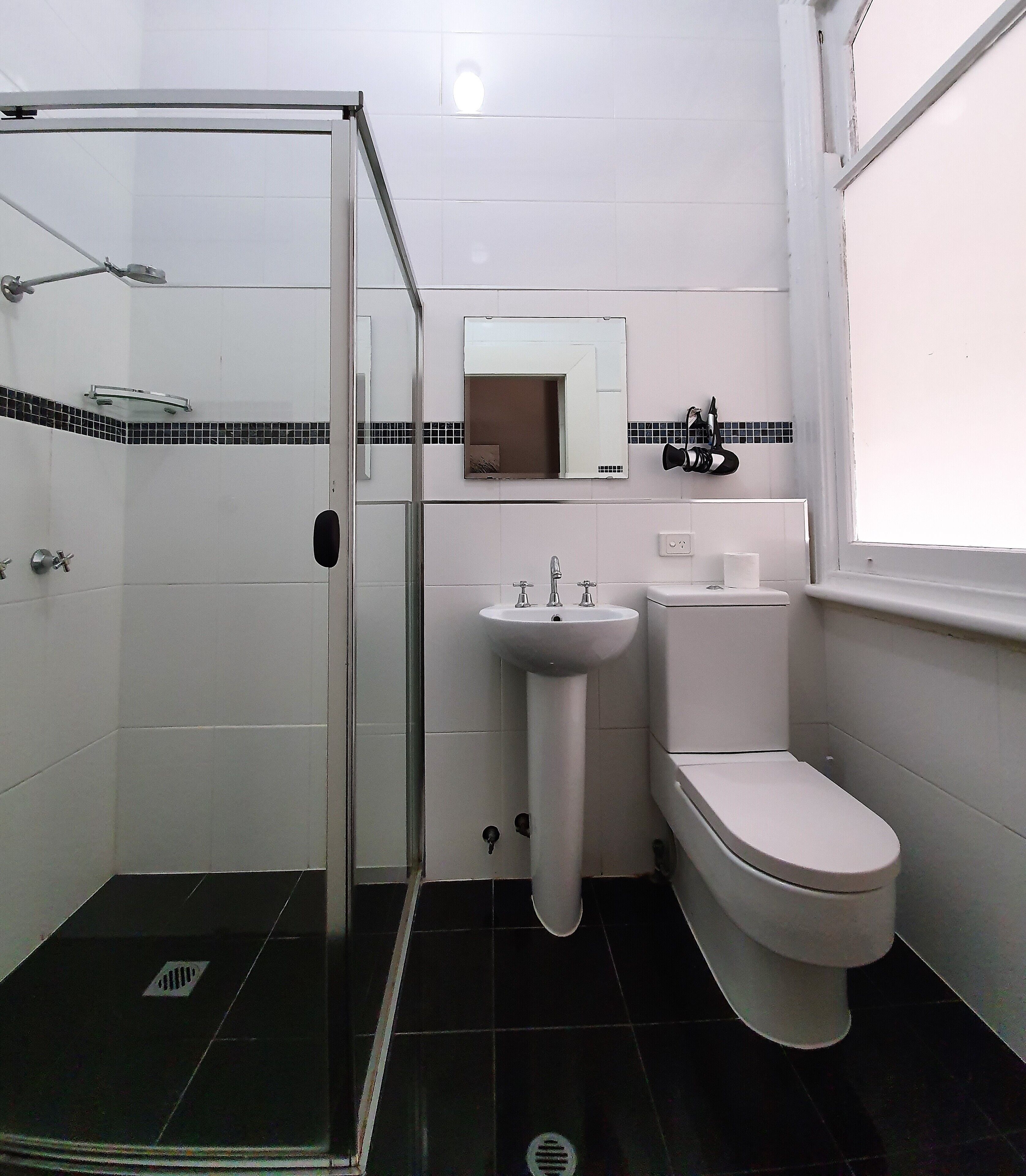 A bathroom with a glass-enclosed shower, a sink, and a toilet.