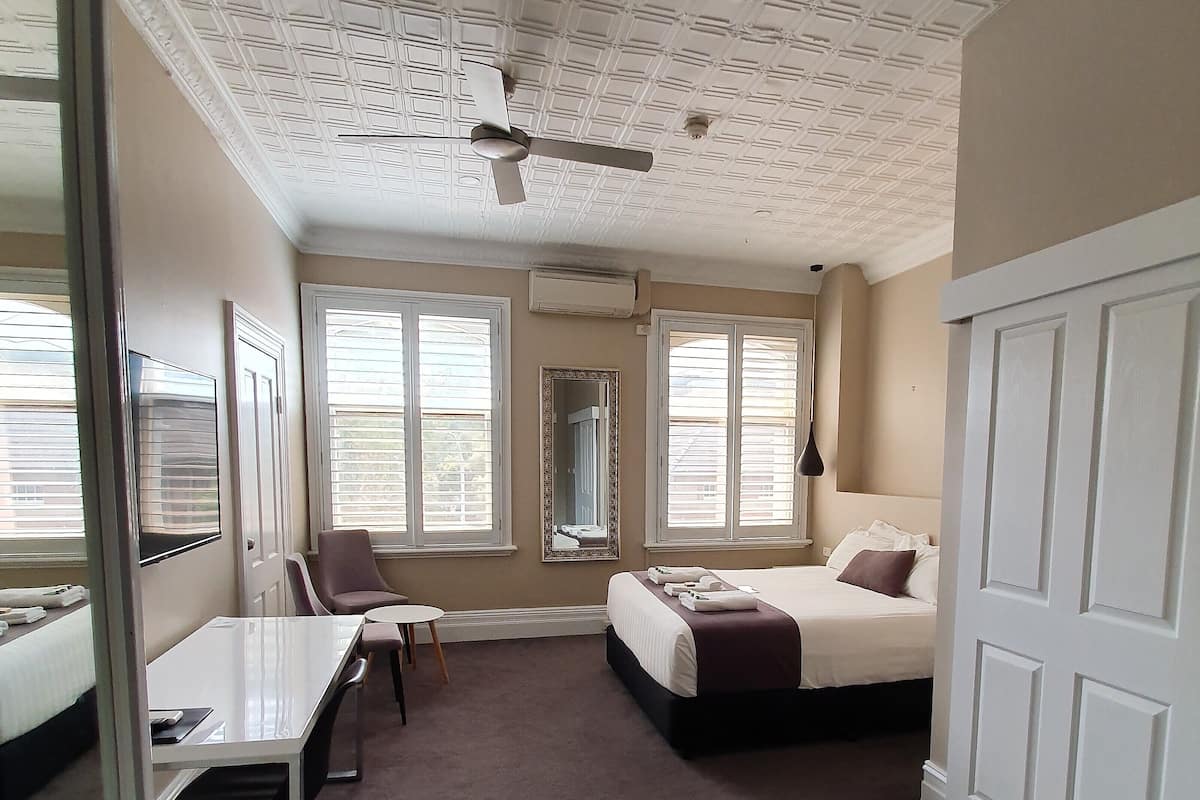 Una habitación de hotel con cama, escritorio, silla y televisor.