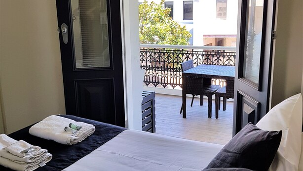 A hotel room with a bed, a door, and a view of the outside balcony. - The Grand Hotel Newcastle (Newcastle)