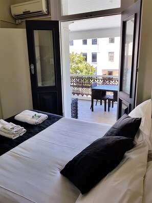 Una habitación de hotel con cama, puerta y vistas al balcón exterior.