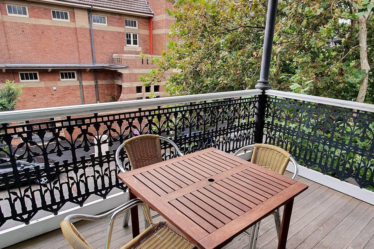 Una terraza de madera con una mesa y dos sillas de mimbre.