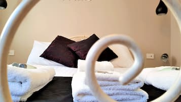 Una cama bien tendida con almohadas blancas y de diseño oscuro, una pared blanca con un letrero que dice 'Dream' y un objeto circular en primer plano.