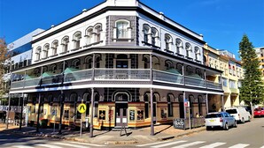A corner building with a balcony, a sign for 'Grand Newcastle', and a pedestrian crossing. - The Grand Hotel Newcastle (Newcastle)