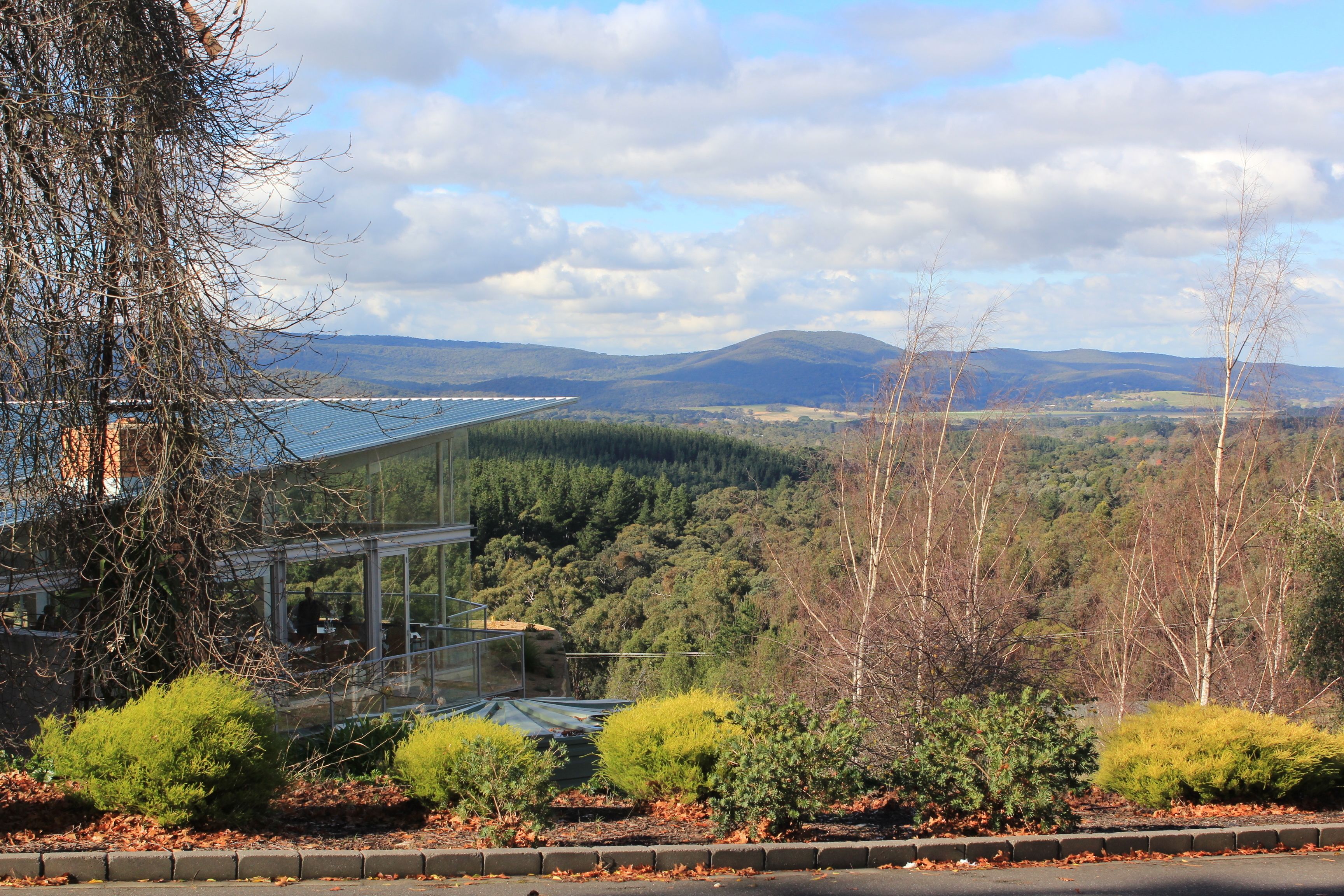 A modern building with a glass facade overlooking a valley.