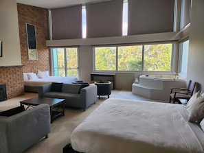 A modern hotel room with a large bed, two sofas, a small table, and a built-in bathtub. - Macedon Ranges Hotel & Spa (Macedon)