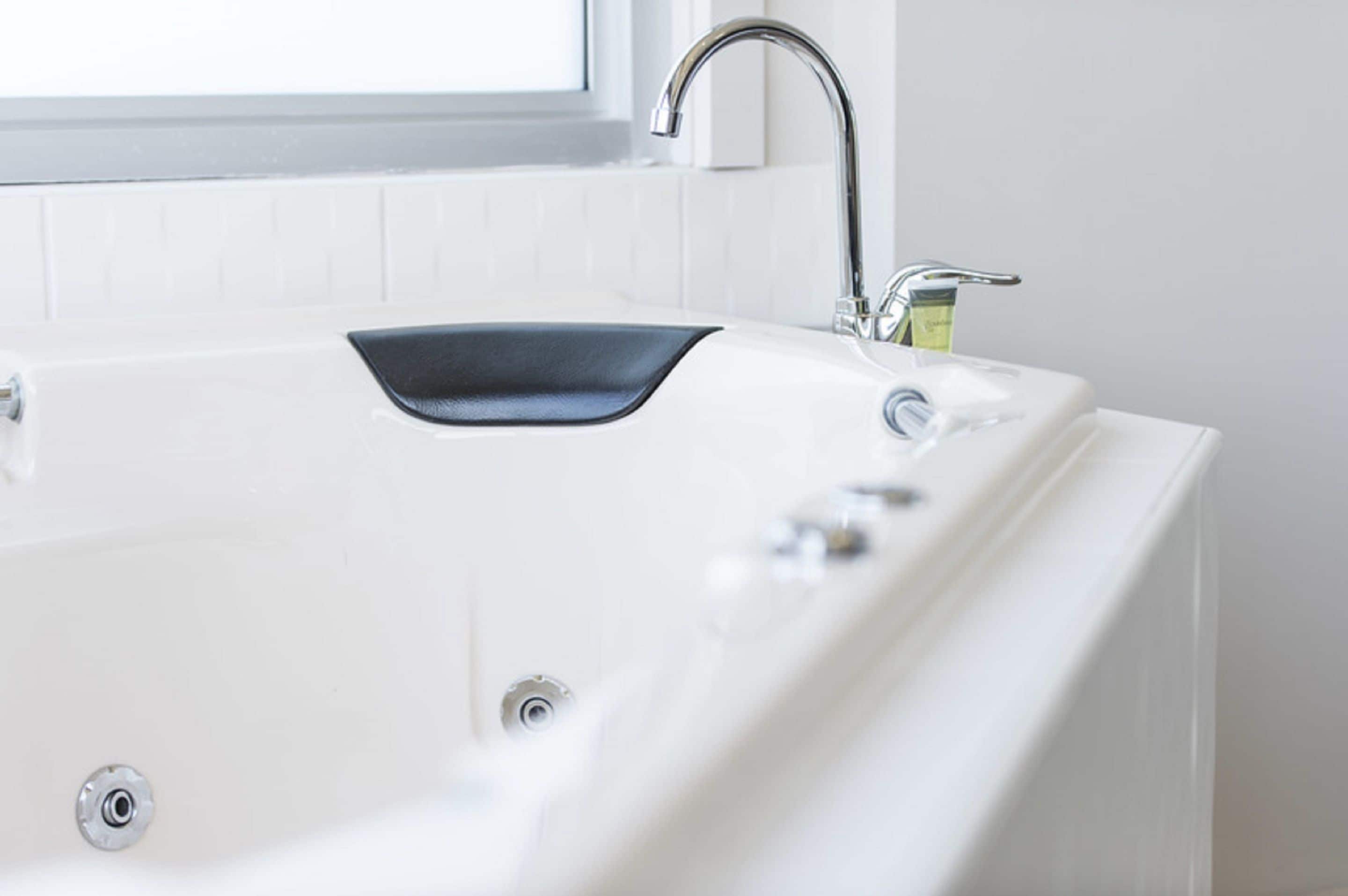 A modern bathroom with a white bathtub, a black sink, and a chrome faucet.