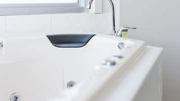 A modern bathroom with a white bathtub, a black sink, and a chrome faucet.