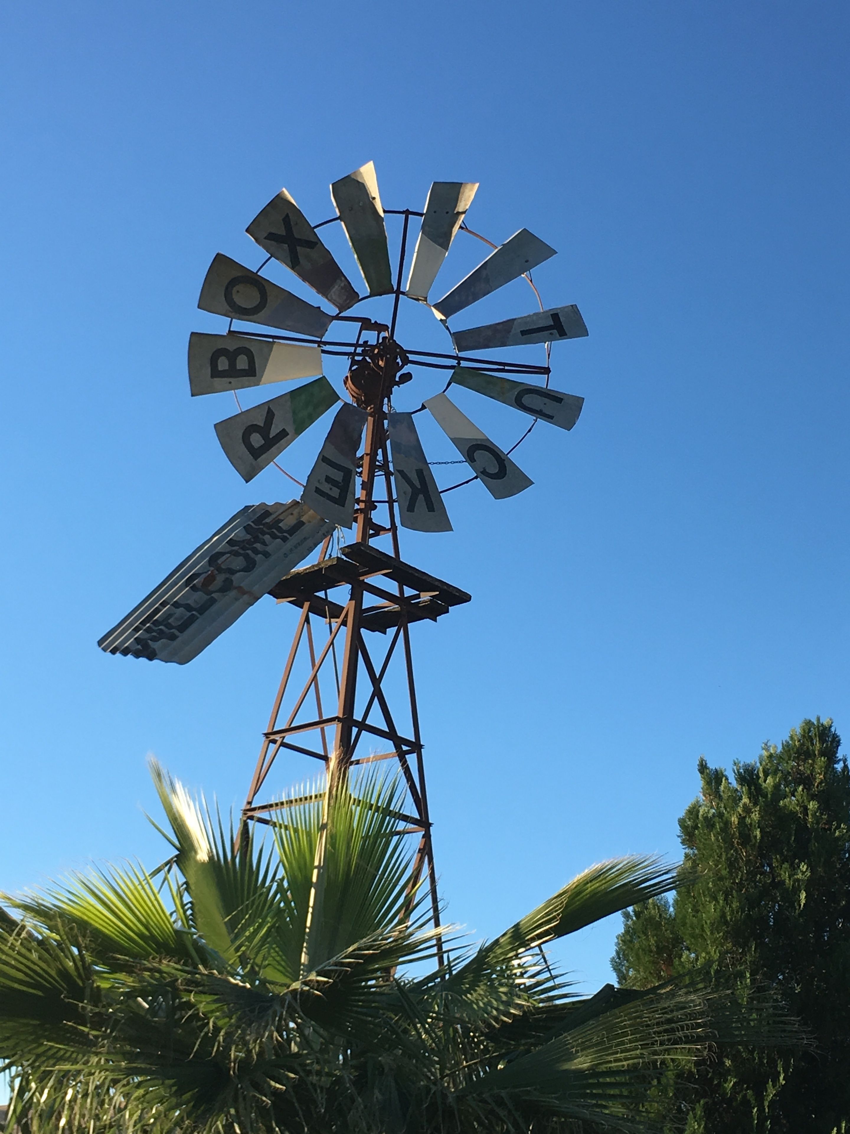 Un molino de viento con las palabras "BOY BOY BOY" escritas en sus aspas, sobre un cielo azul despejado.