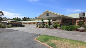 A motel with a covered parking area, a reception desk, and a water tank. - Tuckerbox Motor Inn (South Gundagai)