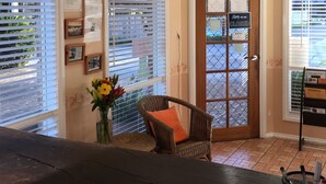 A reception area with a wicker chair, a vase of flowers, and a closed door with a 'Sorry, we are closed' sign. - Tuckerbox Motor Inn (South Gundagai)