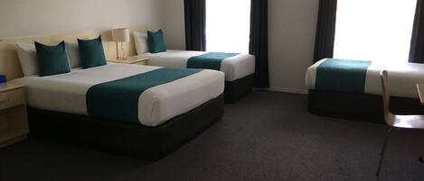 Habitación de hotel con dos camas, una silla, una mesita de noche y aire acondicionado instalado en la pared.